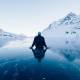 man-sitting-on-a-frozen-lake-looking-at-mountains