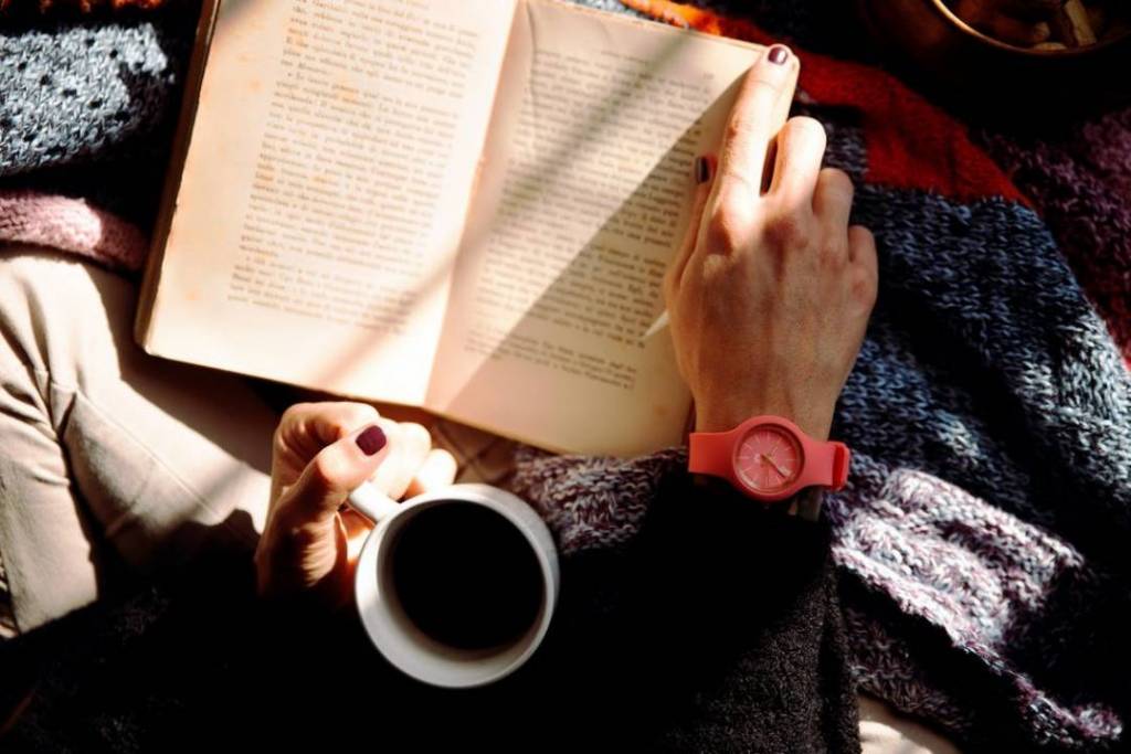 A person reading a book with a cup of coffee